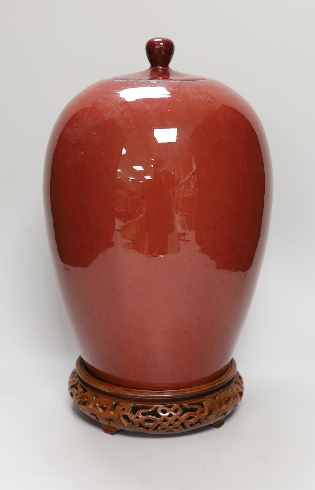 An early 20th century Chinese sang de boeuf jar and cover on hardwood stand, 36cm total